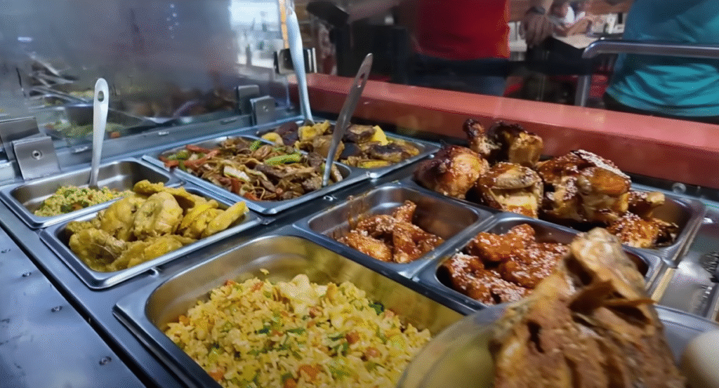 Buffet de comida en bandejas de acero con arroz, pollo y guisos en un mercado de Trujillo.