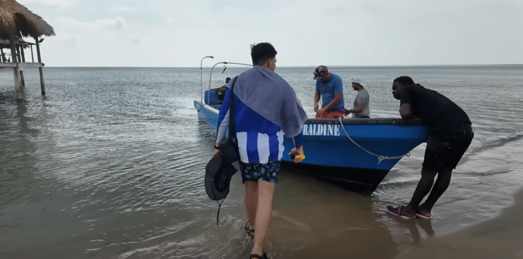 Lancha azul con tripulantes y visitante en la playa de Trujillo, Honduras.