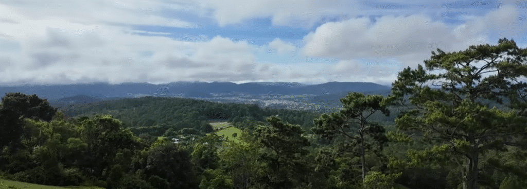 Vista panorámica de un valle verde en Intibucá, con colinas boscosas, áreas de cultivo y montañas a lo lejos bajo un cielo nublado.