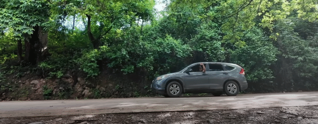 Vehículo SUV gris estacionado en un camino de tierra entre zonas boscosas de Comayagua, con densa vegetación en el fondo.