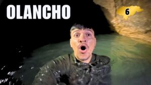 Un hombre dentro del agua en una cueva natural en Olancho, Honduras, levantando la cabeza y con expresión de sorpresa.