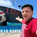 Un hombre señala un barco con calavera y la palabra Isery en Roatán, Islas de la Bahía, Honduras.