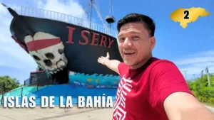 Un hombre señala un barco con calavera y la palabra Isery en Roatán, Islas de la Bahía, Honduras.