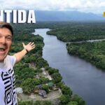 Selfie de un hombre sonriendo con un río ancho rodeado de selva en el departamento de Atlántida, Honduras; el número 1 indica la región en la serie.