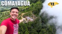 Un hombre se toma una selfie en un mirador de Comayagua con vista a una colina boscosa y un edificio en el centro.