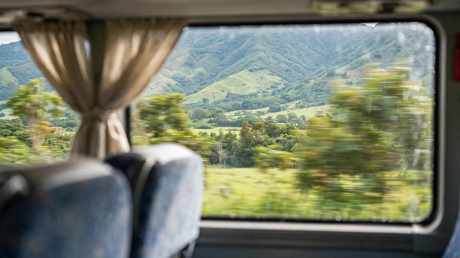 Paisaje de montañas verdes visto desde la ventana de un bus